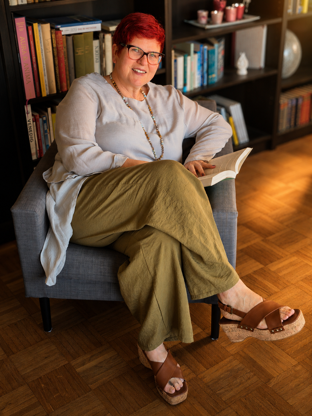 Lis — Buchcoach & Verlegerin, lesend in ihrer Bibliothek
